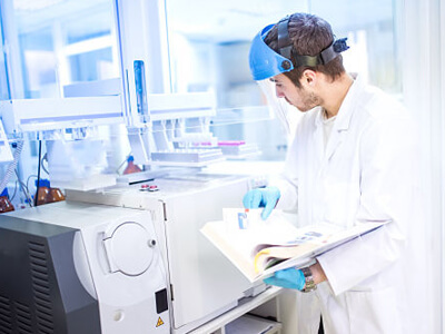 Scientist using manual for programming a chemical computer machinery in laboratory