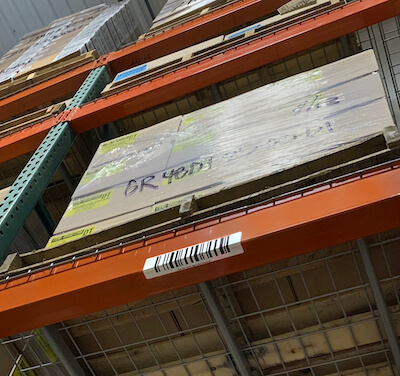 Retroreflective warehouse rack label wrapped beneath beam face