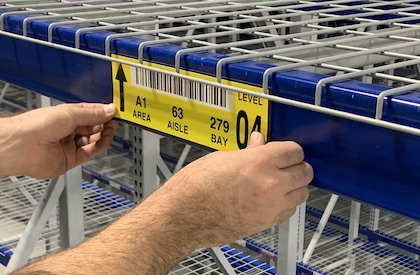 worker applying warehouse magnet label to new racking